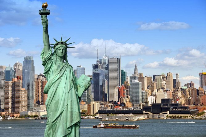 Statue of Liberty with Manhattan skyline across the harbor and a boat sailing in the river.